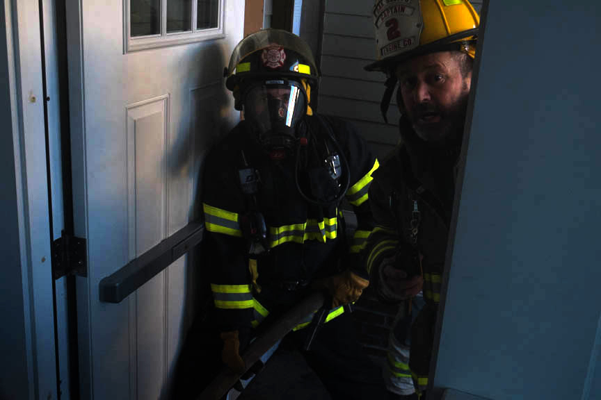 Firemen prepare entry into smoke filled building.