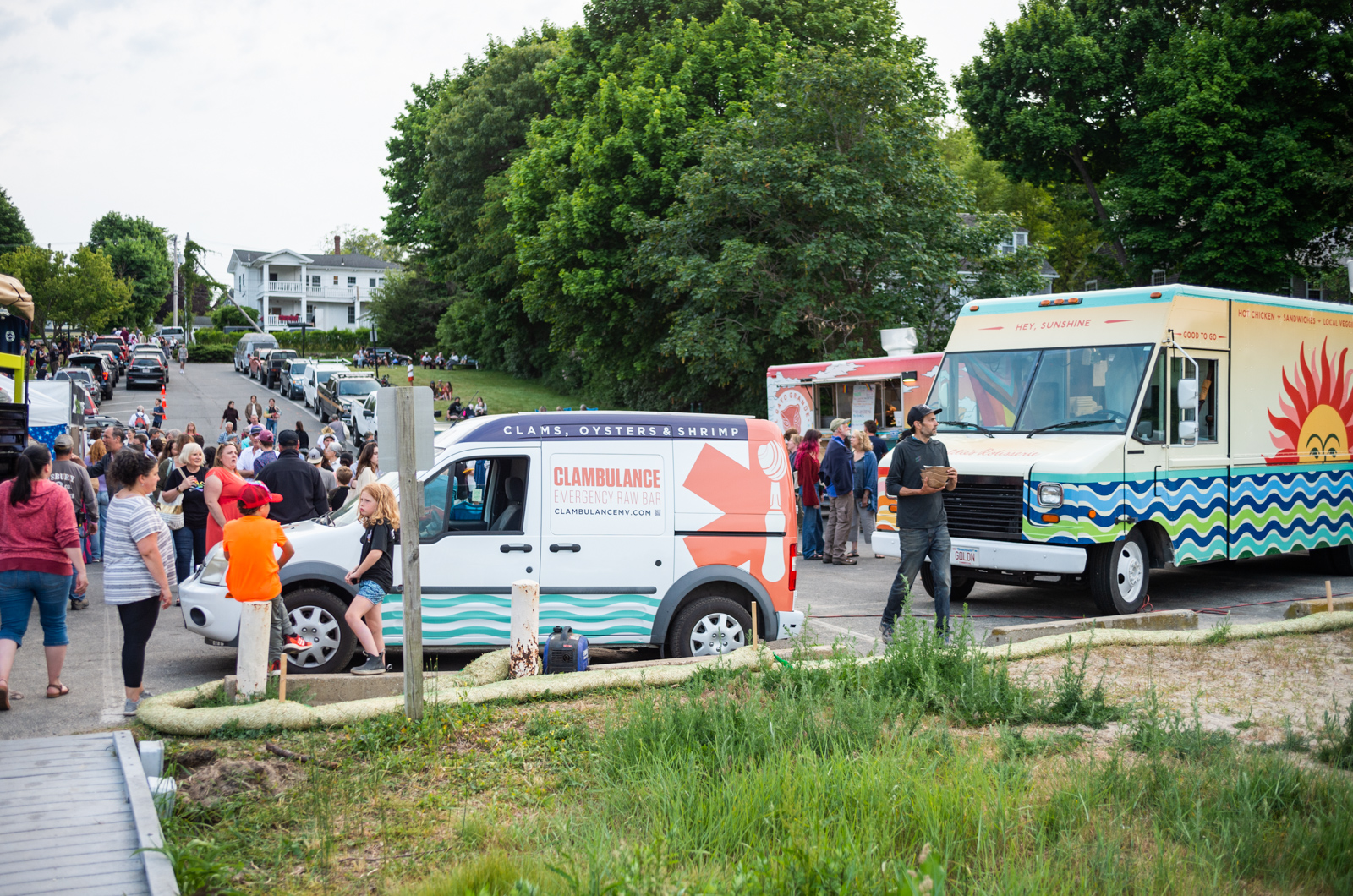 Several food trucks including The Hungry Farmer, The Clambulance, and Goldie's line the parking lot.