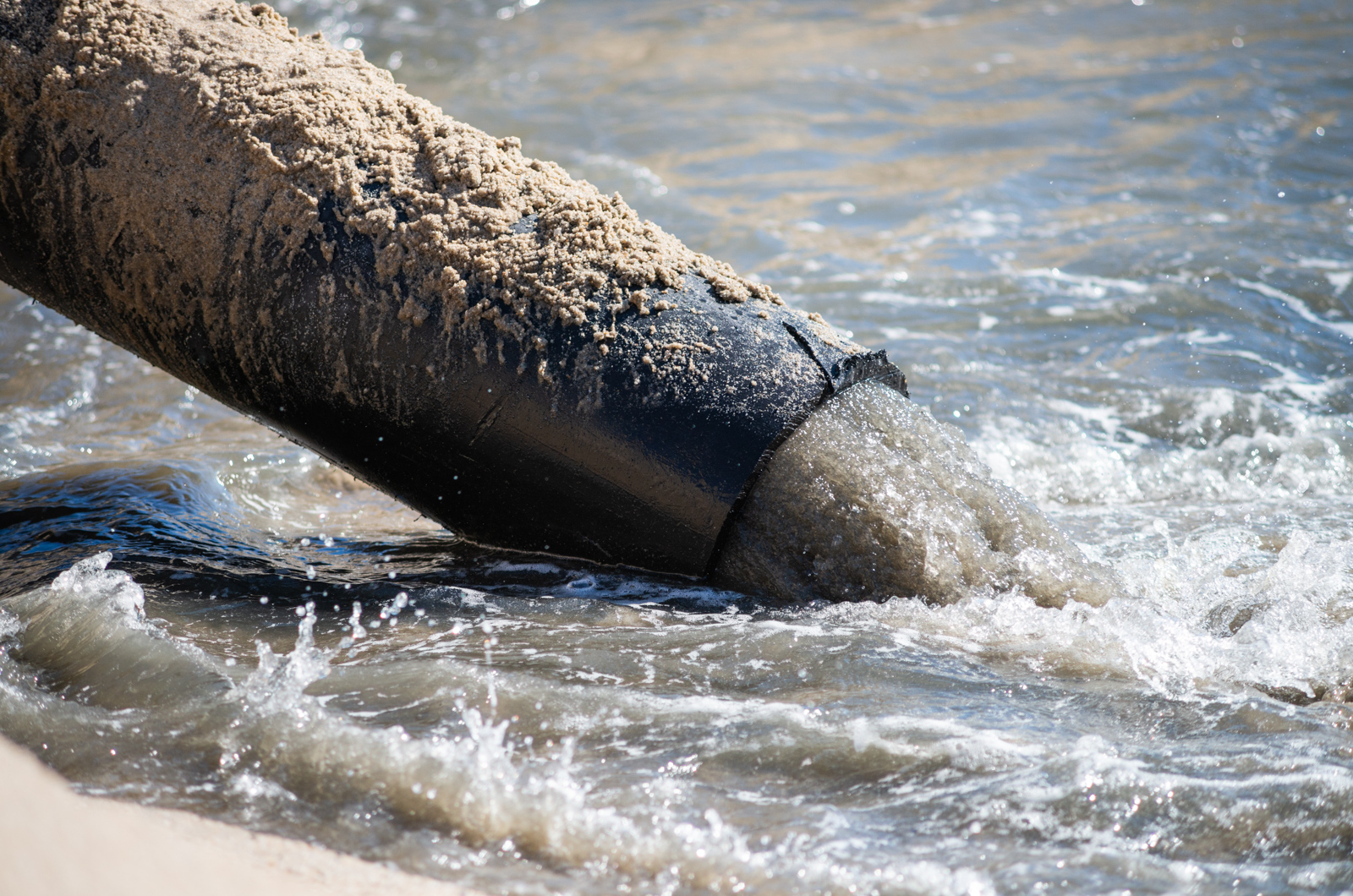 Slurry pours out of dredge pipe.