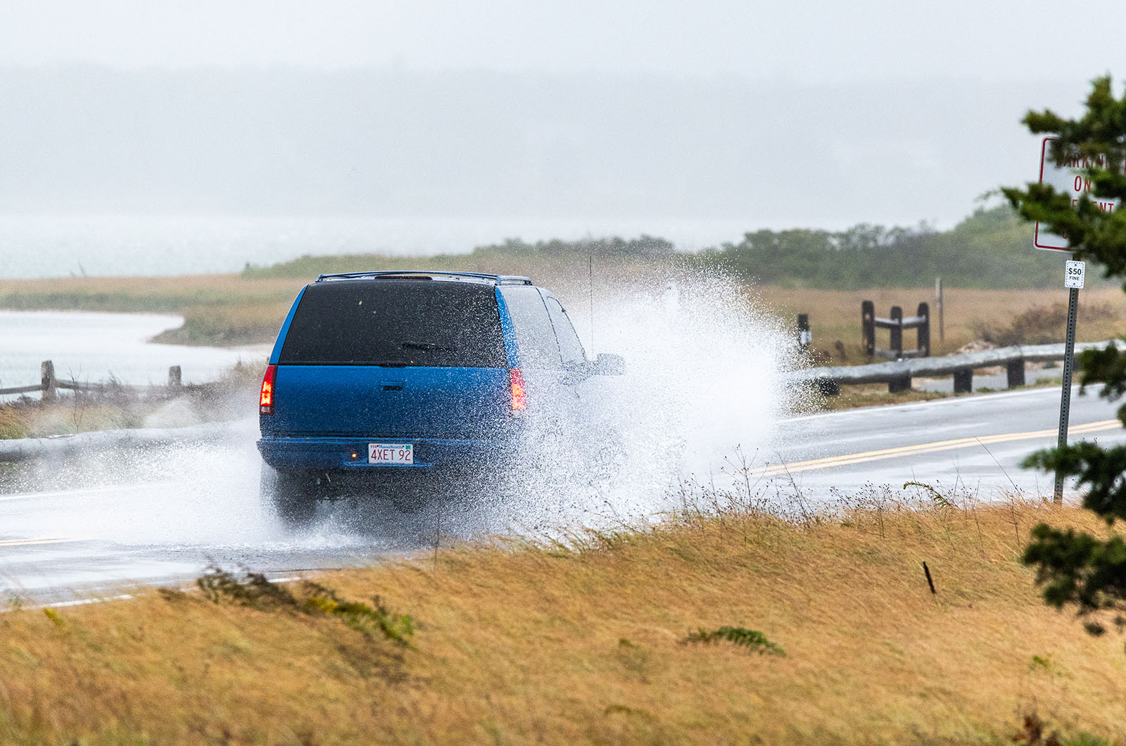 Vehicle drives through coastal flooding along State Beach in Edgartown.
