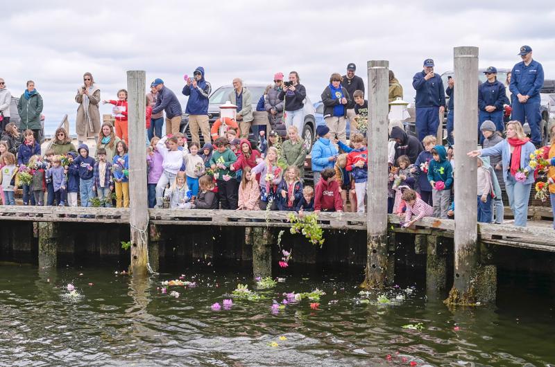 Chilmark school students throw their flowers in the harbor.