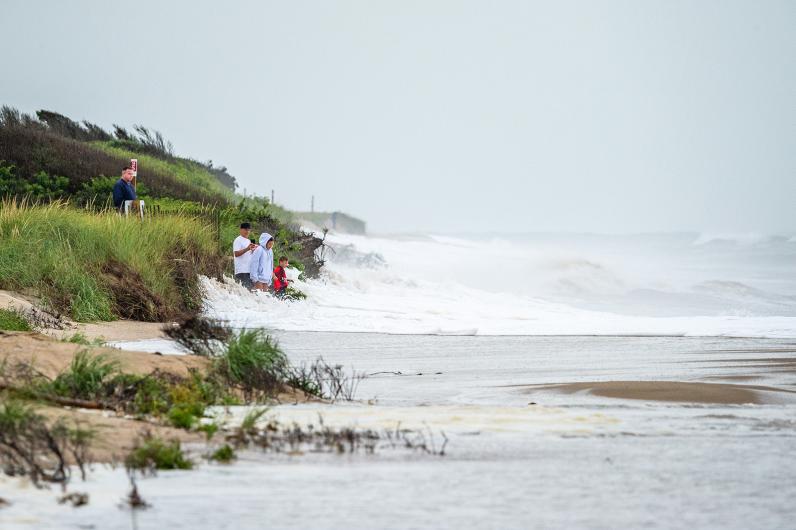 Onlookers dodge waves near the dunes.