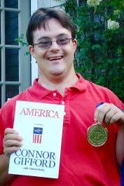 author holds up his book and medal