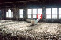 The third floor has been completely stripped with concrete and drywall rubble covering the floor.