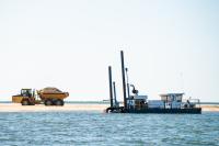Trucks take sand from dredge site toward South Beach.