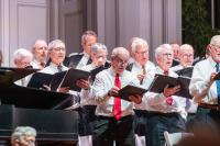The men of the chorus keep their eye on the conductor.